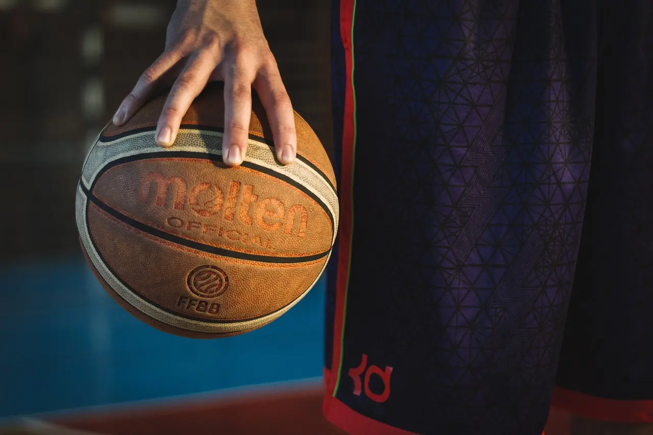 Hånd holder basketball ved siden af spiller